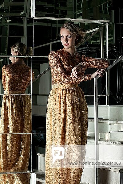 Schlanke Blondine posiert in modischem goldenen Kleid  Nahaufnahme
