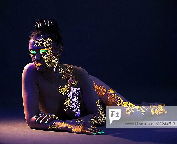 Attraktives nacktes Mädchen mit UV Makeup posiert im Studio  Nahaufnahme
