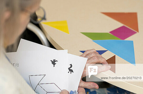 EHPAD - An elderly resident playing at reconstructing geometric figures on a table in the common room.