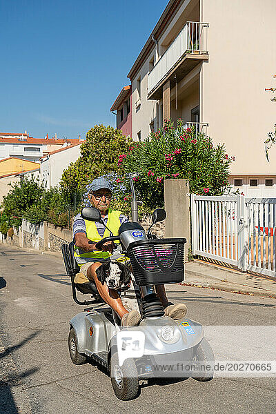90-year-old senior walking on his electric scooter  with his dog.