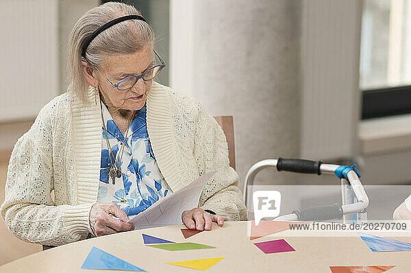 EHPAD - An elderly resident playing at reconstructing geometric figures on a table in the common room.