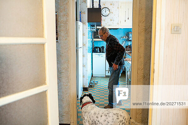 Loneliness of the elderly person  senior living alone with their dog in front of their refrigerator door.