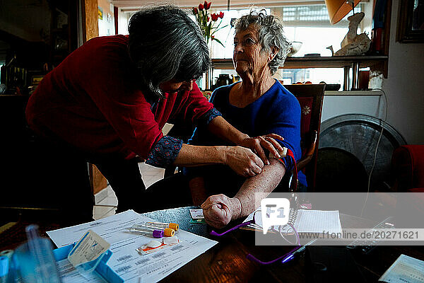 Home visit by a nurse to an elderly person. The nurse takes a blood test.