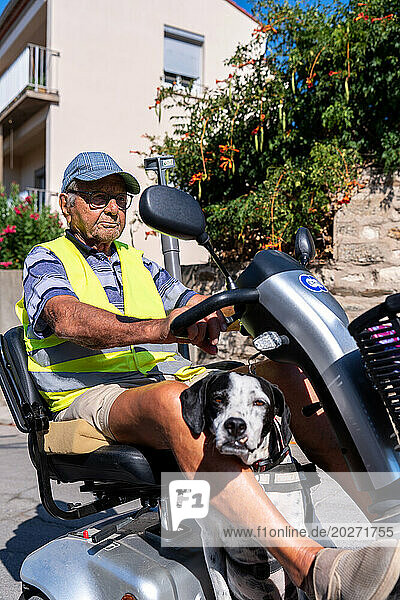 90-year-old senior walking on his electric scooter  with his dog.