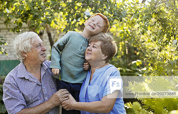 Smiling boy having fun with grandparents in garden
