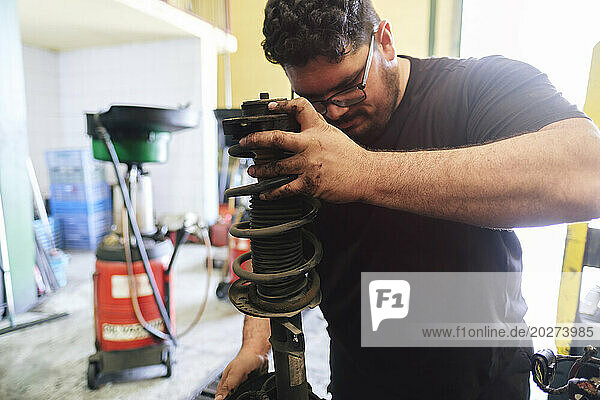 Mechanic removing vehicle machine parts at workshop