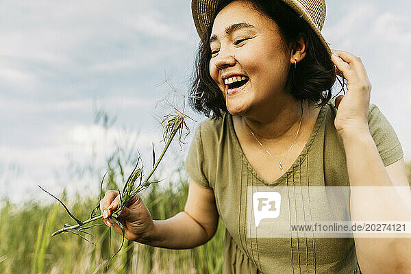 Happy mature woman with dandelion in field