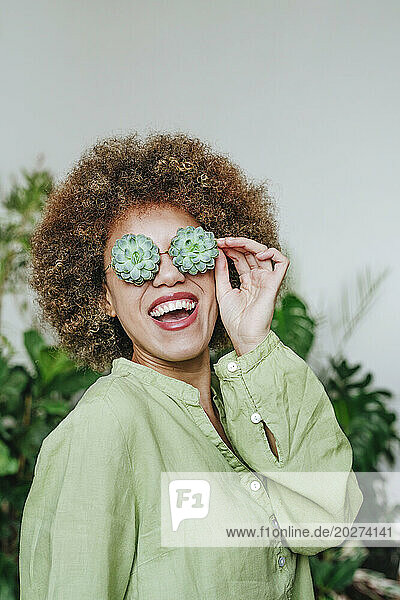 Happy young woman wearing eyeglasses with flowers of succulent plant