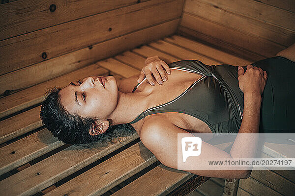 Young woman lying on bench at sauna