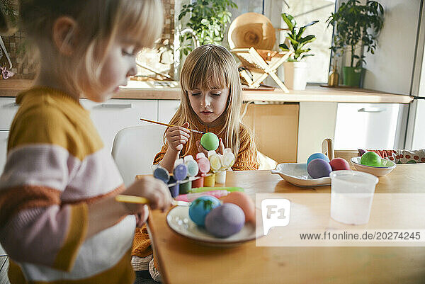Sisters painting Easter eggs at home