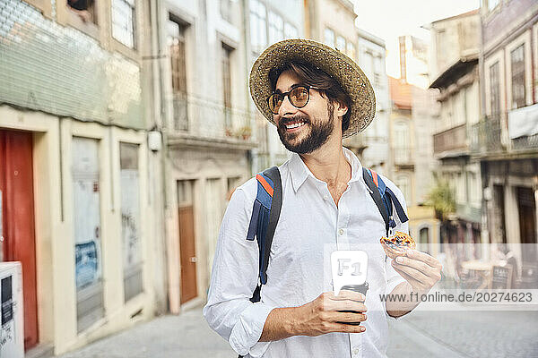 Smiling man holding coffee cup and traditional dessert pastel de nata