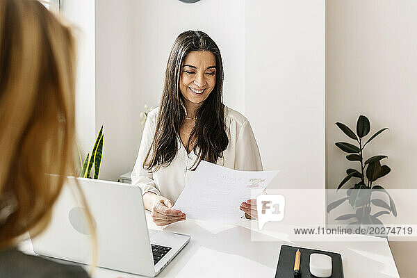 Smiling recruiter looking at candidate's resume in office