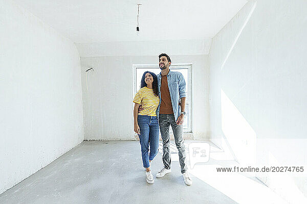 Happy young couple standing at new home