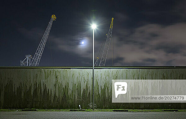 Netherlands  South Holland  Rotterdam  Old harbor cranes seen from behind surrounding wall at night