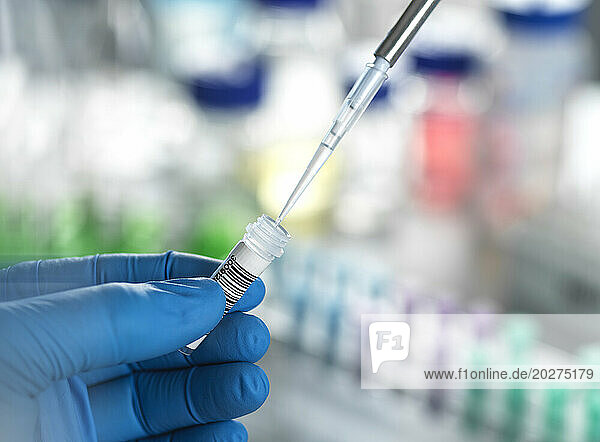 Hands of scientist pipetting DNA sample in vial at laboratory