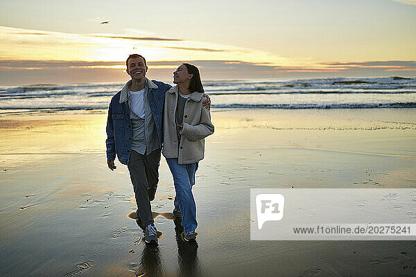 Smiling man walking with girlfriend on ocean beach