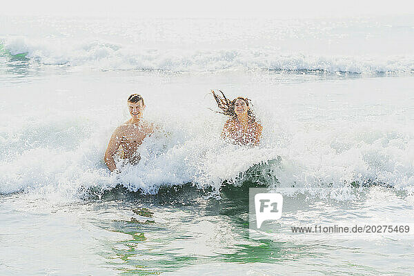 Playful couple having fun in water at beach