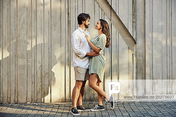 Loving young couple standing in front of wall