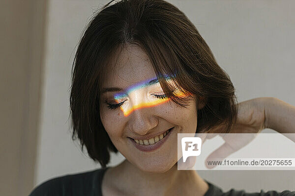 Smiling young woman with multi-colored light on face