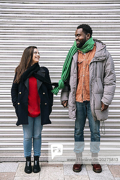 Smiling couple wearing tied scarves and standing in front of shutter