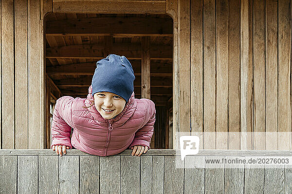 Smiling girl leaning on wooden railing at cabin