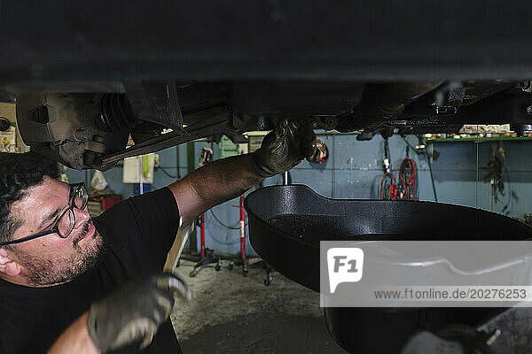 Mechanic using wrench to remove vehicle parts at workshop