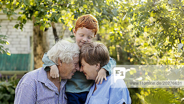 Happy senior couple with face to face near grandson in garden