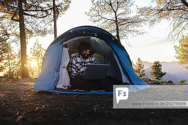 Smiling freelancer working on laptop at sunset