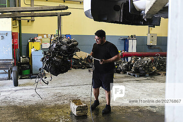 Mechanic standing and examining engine at workshop