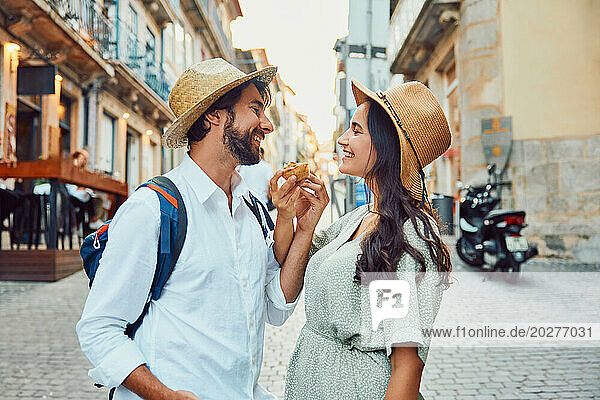 Happy couple holding traditional dessert near buildings
