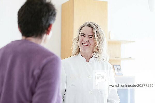 Smiling mature doctor talking to patient at hospital