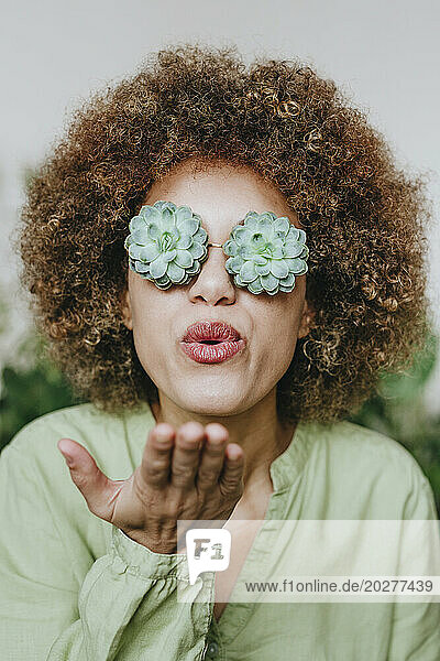 Woman wearing wearing echeveria flowers eyeglasses and blowing kiss