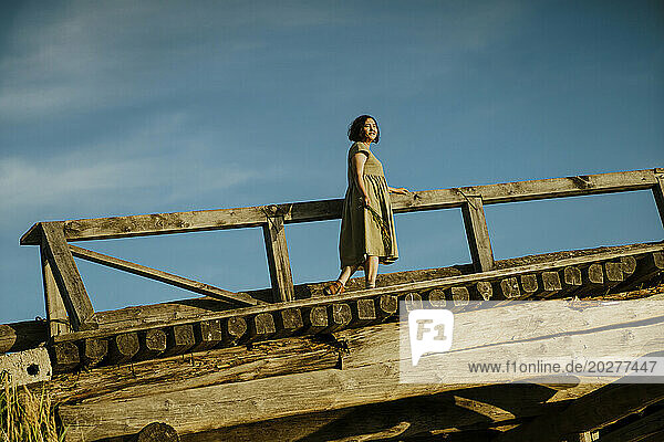 Carefree mature woman walking on bridge under blue sky