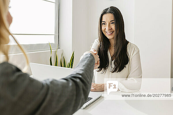 Smiling recruiter shaking hands with candidate at office