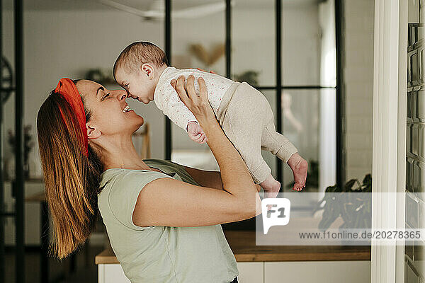 Happy mother playing with baby girl at home