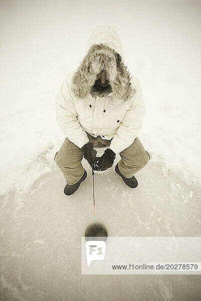 USA  NY  Hammond  High angle view of man ice fishing on frozen Black Lake