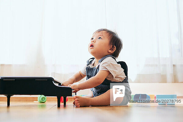 A baby playing with a toy piano