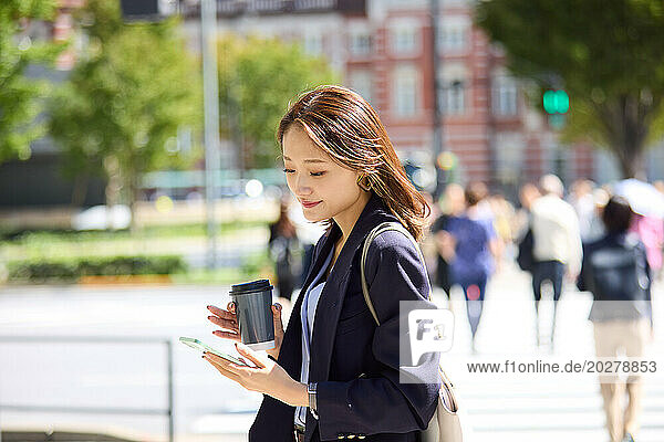 Asian woman using smartphone while walking on the street