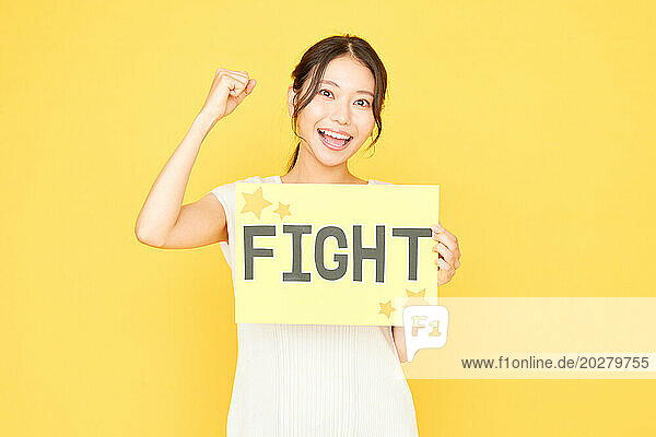 Woman holding fight sign on yellow background