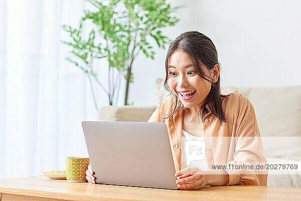 Asian woman using laptop in living room