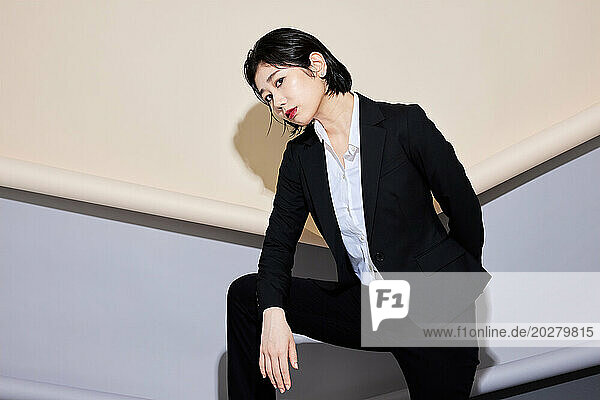 A woman in a business suit standing against a wall