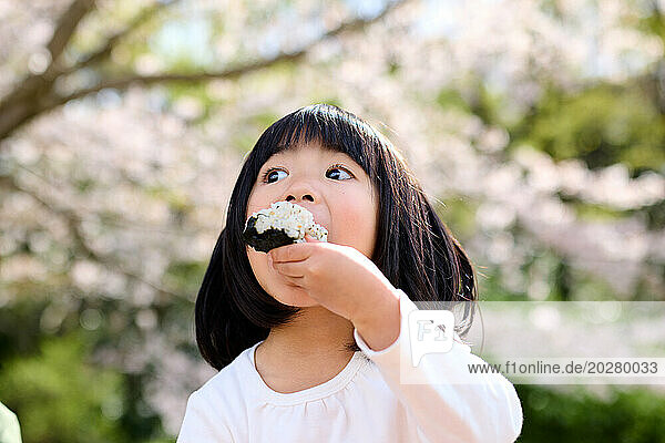 A little girl eating a rice ball