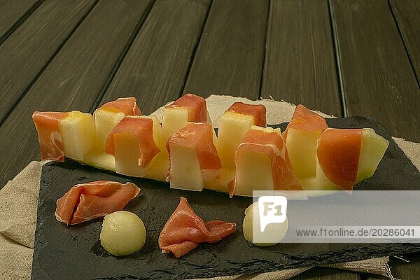 Saftige Melone mit Schinken typisches Sommergericht auf dunklem Hintergrund