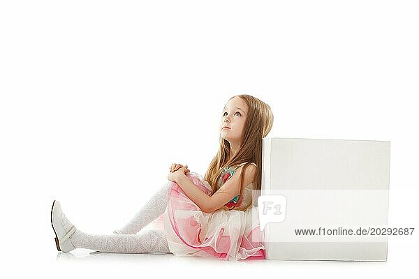Verträumtes kleines Mädchen posiert mit Würfel im Studio  vor weißem Hintergrund
