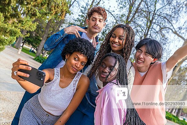 Dynamische Aufnahme einer Gruppe fröhlicher multiethnischer Freunde  die zusammen ein Selfie in einem Park machen