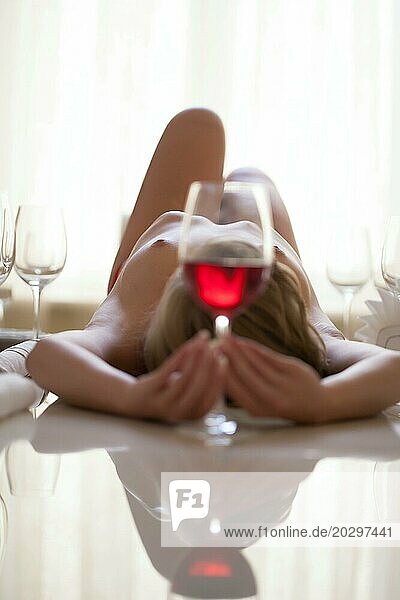 Porträt einer nackten  schlanken Frau mit einem Glas Wein