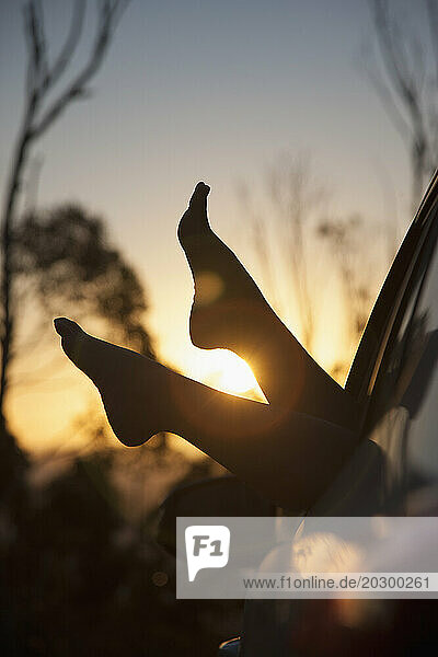 Woman's Feet Sticking out of Car Window at Sunset