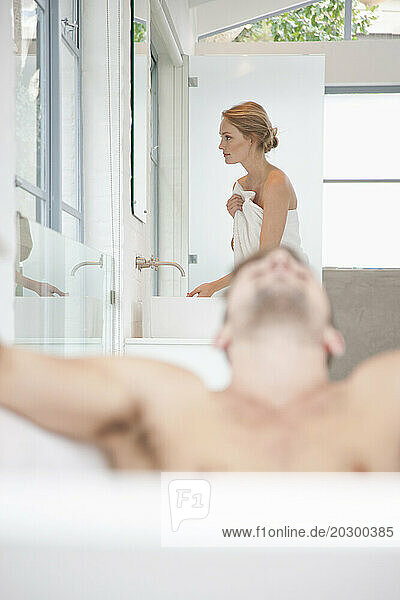 Man Relaxing in Bathtub  Woman in Background
