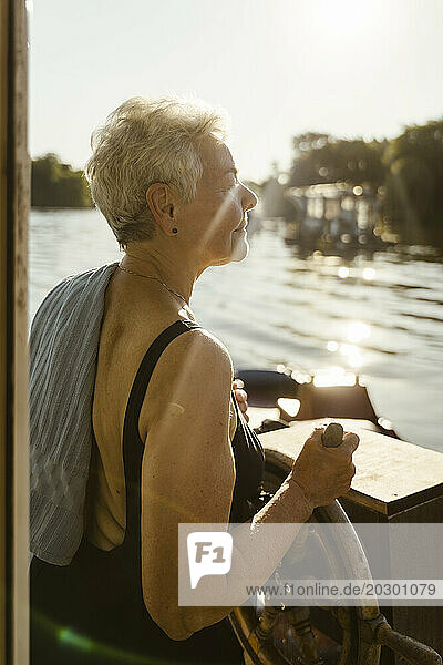 Senior woman steering houseboat on vacation