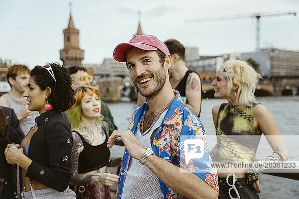 Portrait of smiling gay man wearing floral pattern and dancing with non-binary friends in city